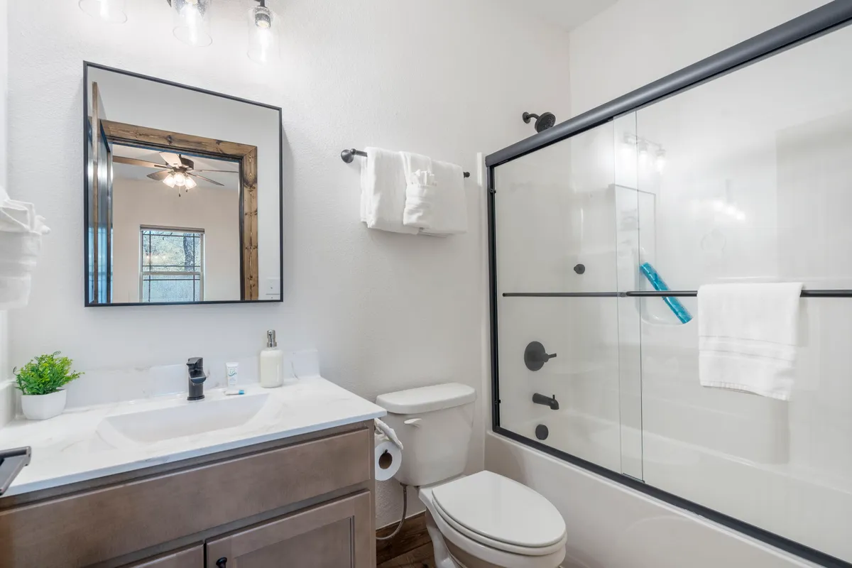 An inviting ensuite bathroom featuring a modern vanity with sink, a large mirror, a glass-enclosed shower, and plush towels, providing a sense of private luxury and relaxation.