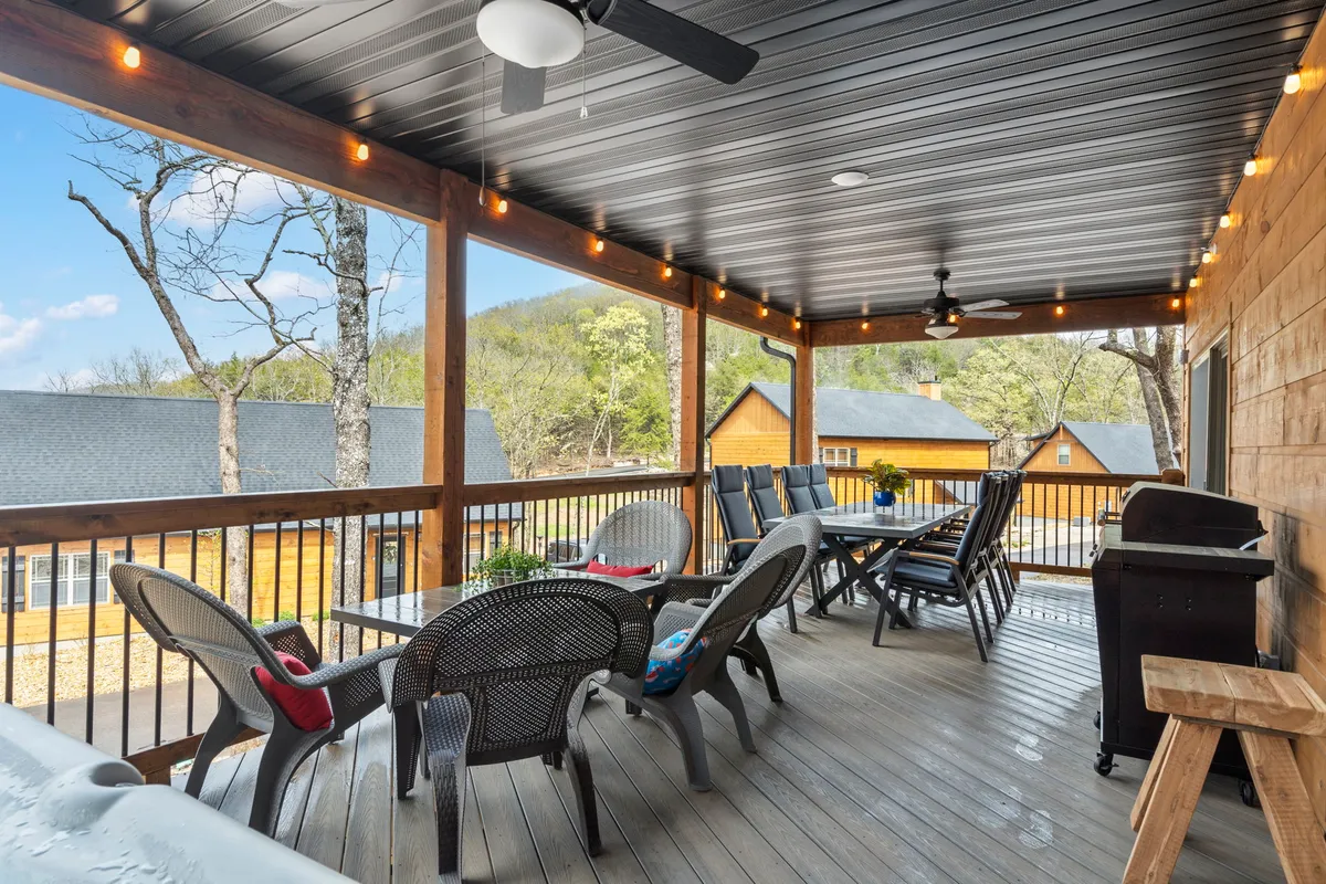 A deck area with outdoor seating, a grill, and a panoramic view of the mountains. The setting encourages outdoor dining, barbecuing, and relaxed conversation as the sun sets over the landscape.