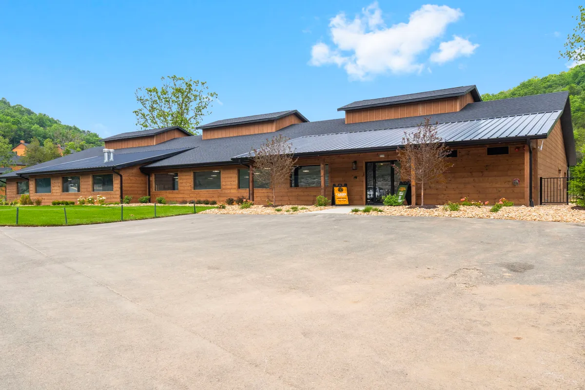 This image highlights the property's wooden facade and landscaped front yard, with a modern roofline and inviting patio space. The scene exudes a welcoming atmosphere and hints at both ample outdoor space and easy access for guests and their pets.
