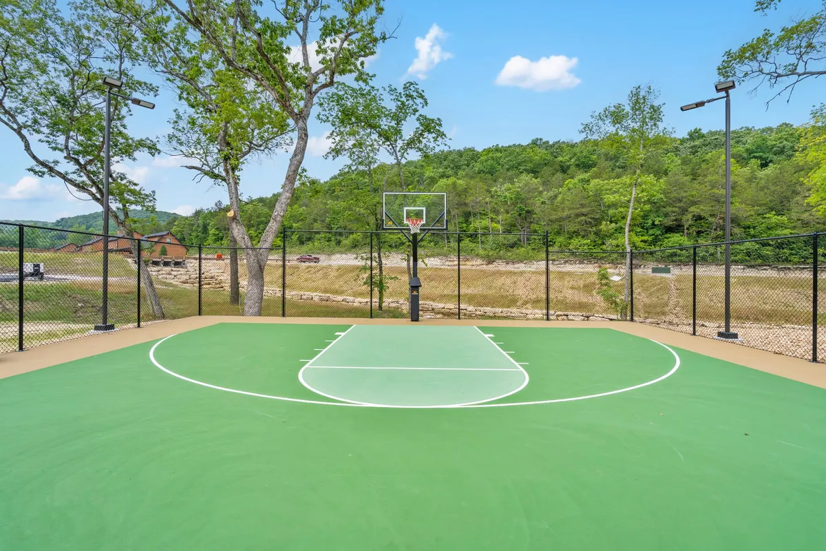 This exterior shot shows a basketball court set among trees, with a hoop ready for friendly competition. The open, energetic environment invites active play for guests of all ages.