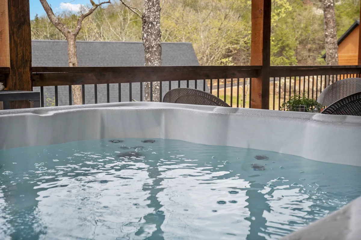 An outdoor hot tub nestled on a private deck, surrounded by trees and furnished with comfortable seating. The atmosphere is tranquil and conducive to stargazing or socializing with friends over drinks.